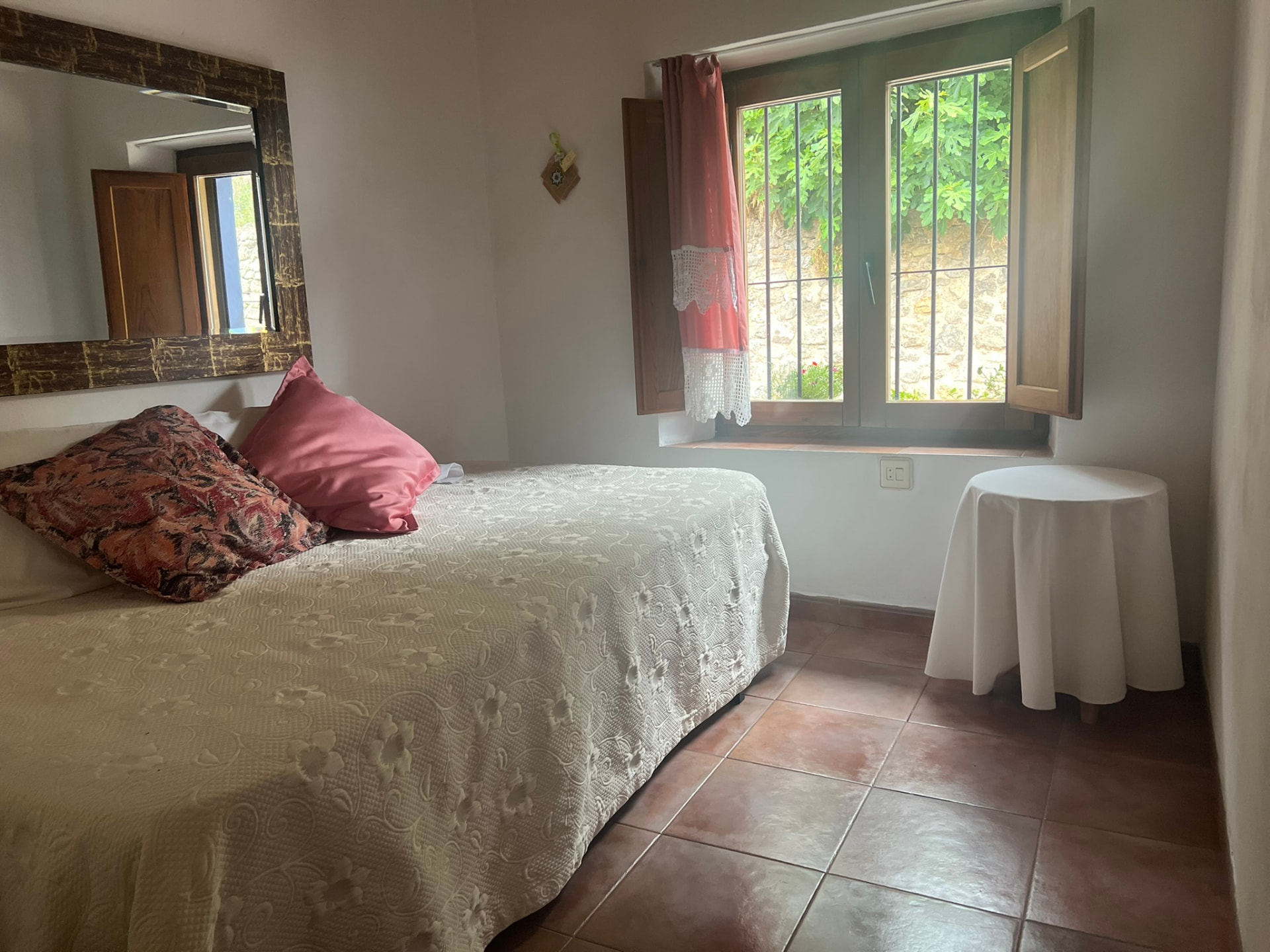 Dormitorio de matrimonio con espejo y ventana al patio del apartamento El Hontanar