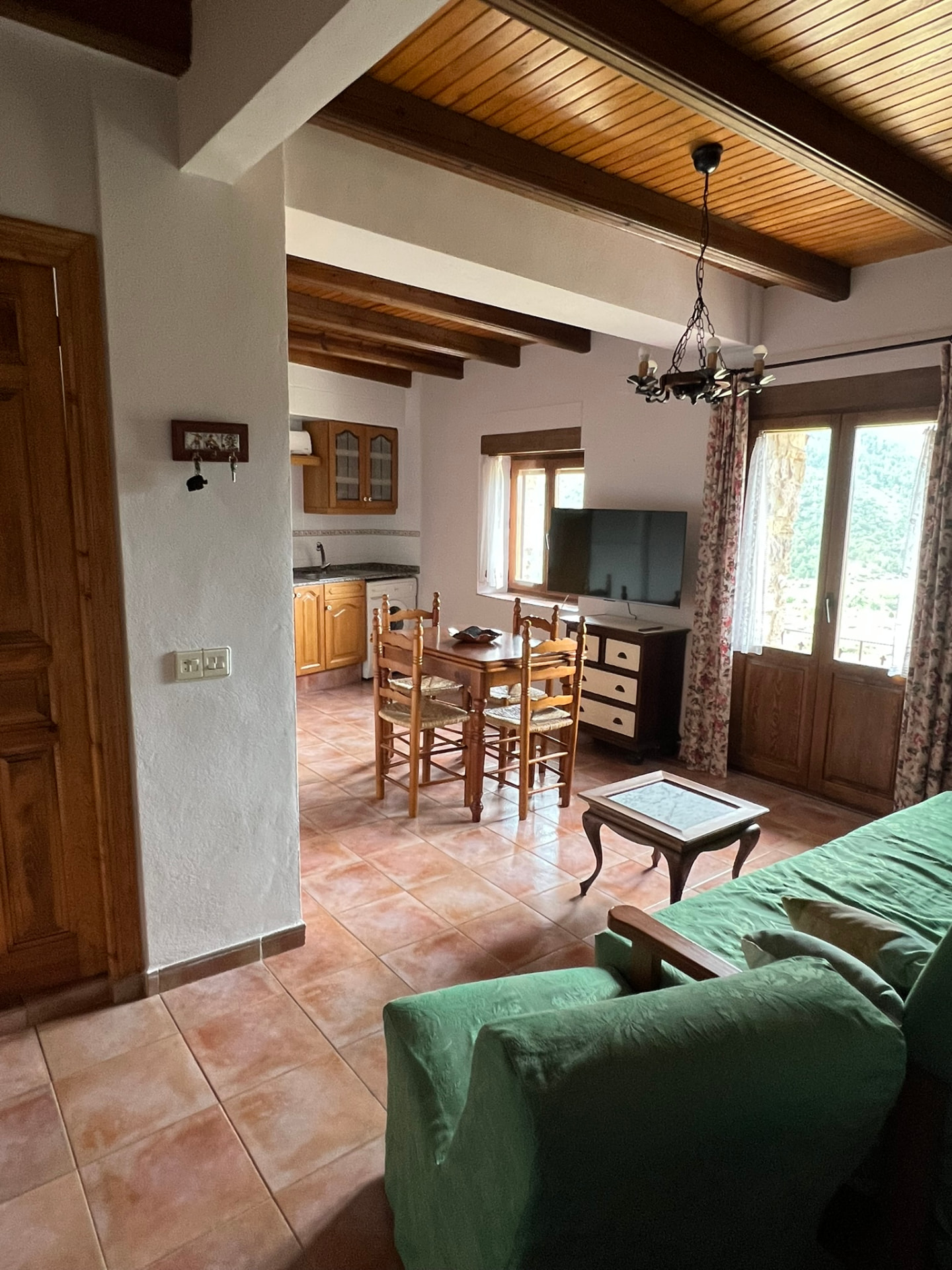 Salón con vigas de madera y cocina abierta del apartamento El Hontanar