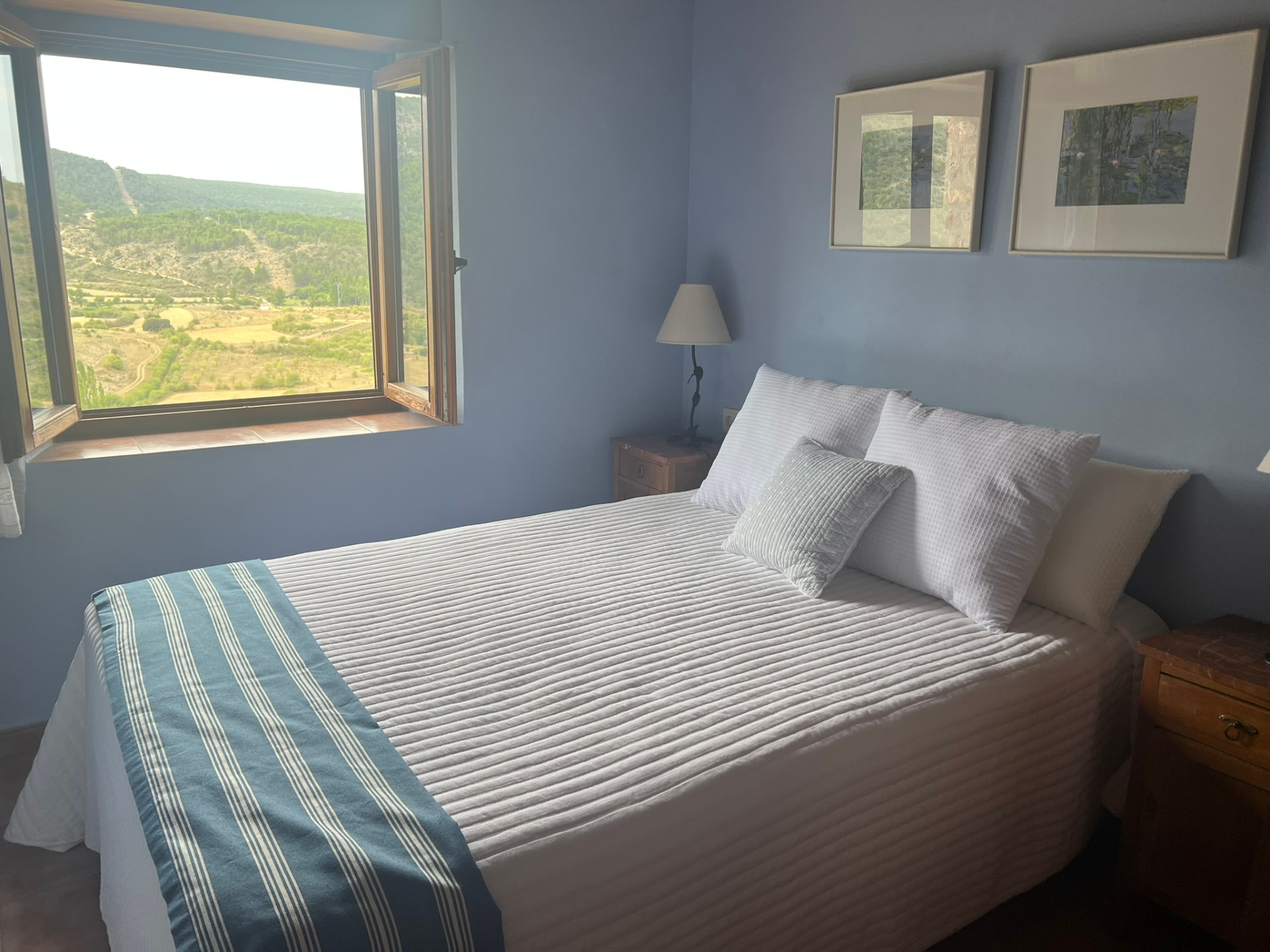 Dormitorio azul con cama de matrimonio y ventana con vistas al valle en El Hontanar